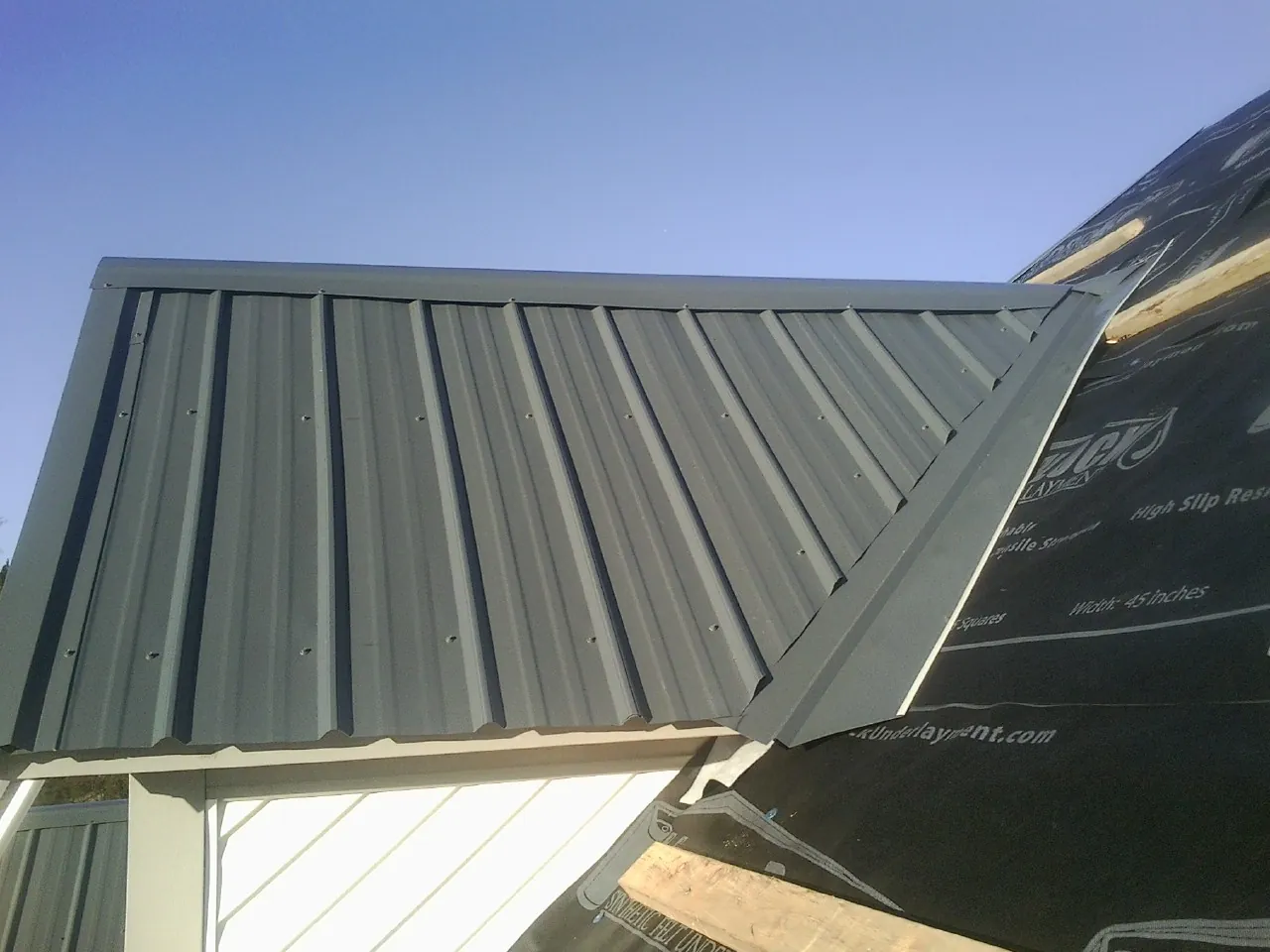 Gray metal roof panels going on over a garage gable in Hebron